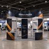 20x20 Island Booth with Curved Wall Panels & Display Shelving